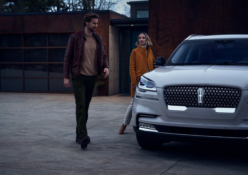 A man and a woman approaching a 2024 Lincoln Aviator® SUV, which illuminates certain lights when they are close | Koons Lincoln of Bethesda in Silver Spring MD