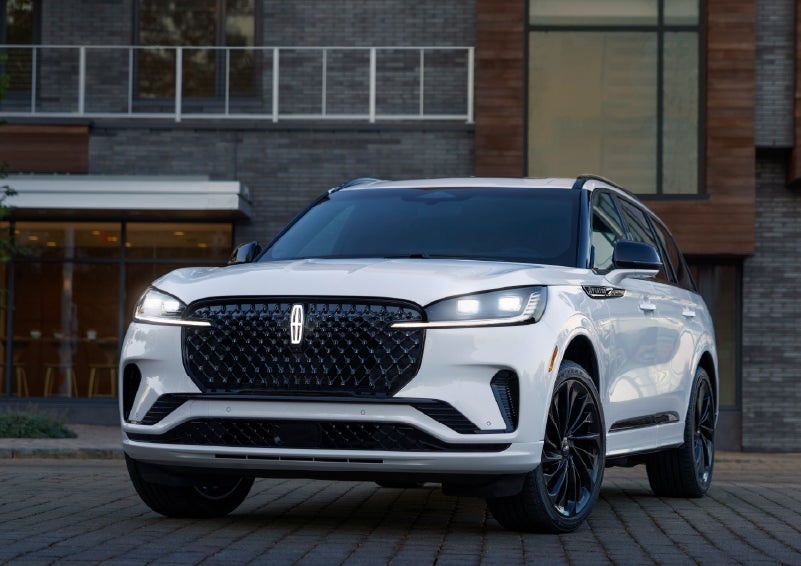 A 2026 Lincoln Aviator® Reserve model is shown with the available Jet Appearance Package parked near a restaurant. | Koons Lincoln of Bethesda in Silver Spring MD