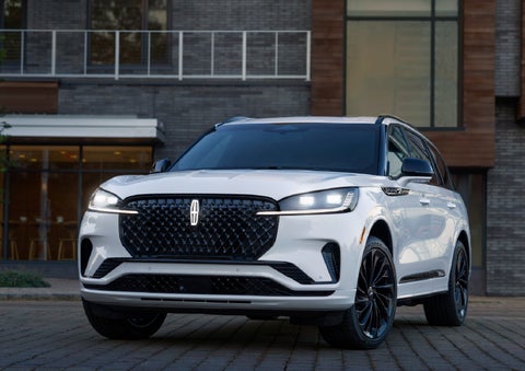 A 2026 Lincoln Aviator® Reserve model is shown with the available Jet Appearance Package parked near a restaurant. | Koons Lincoln of Bethesda in Silver Spring MD