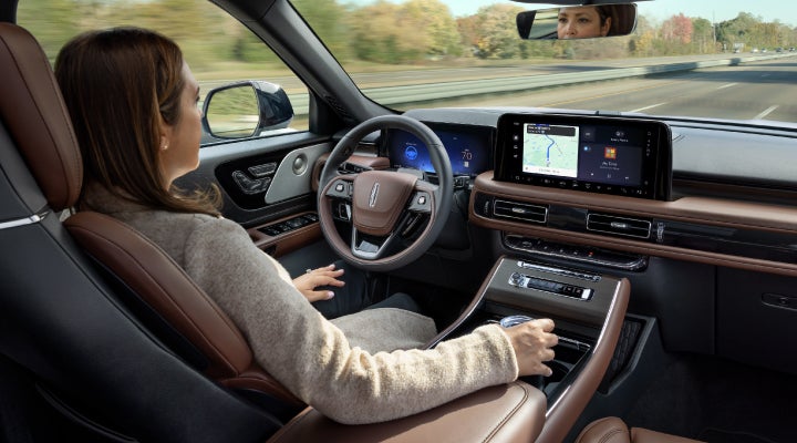 A 2026 Lincoln Aviator® SUV is being driven hands-free on a highway near a forest | Koons Lincoln of Bethesda in Silver Spring MD