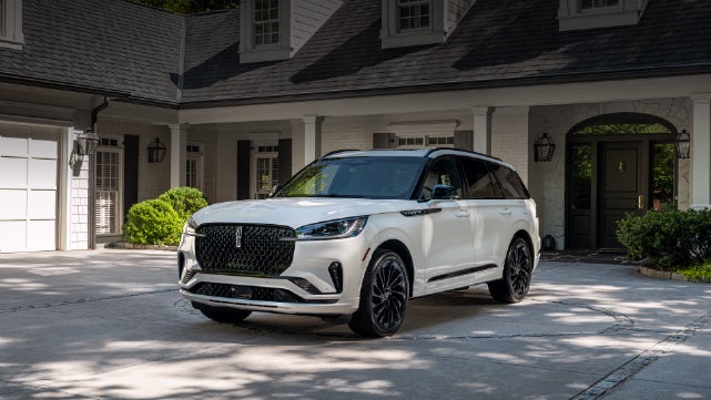 A white 2026 Lincoln Aviator® SUV is parked in the driveway of a luxury home. | Koons Lincoln of Bethesda in Silver Spring MD