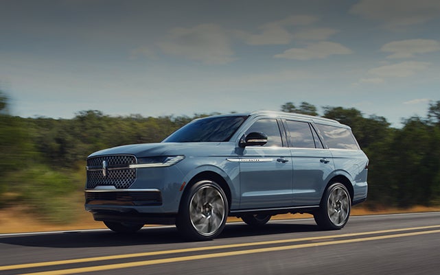 A 2027 Lincoln Navigator® SUV is being driven on a rural highway