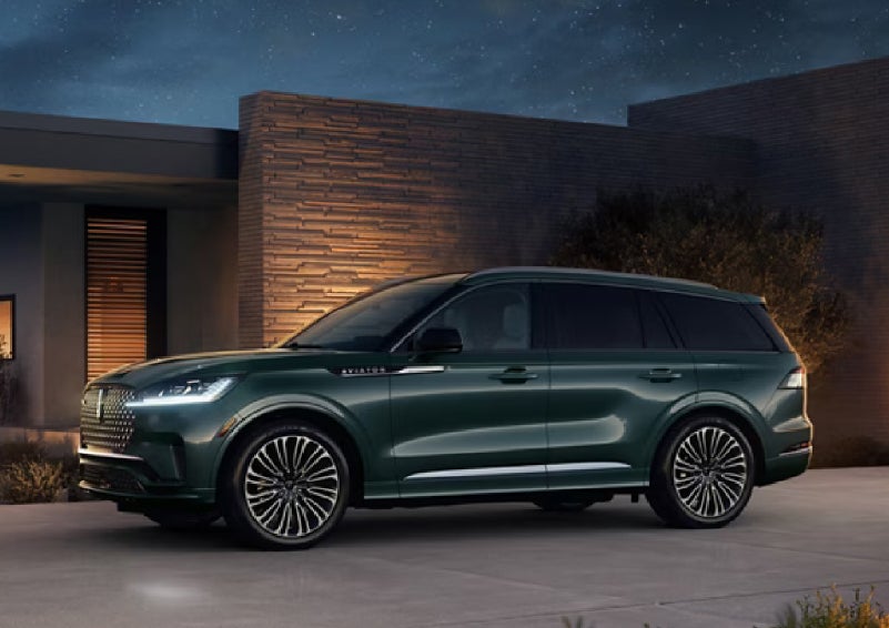 A green 2027 Lincoln Aviator® SUV is parked outside a contemporary home. | Koons Lincoln of Bethesda in Silver Spring MD