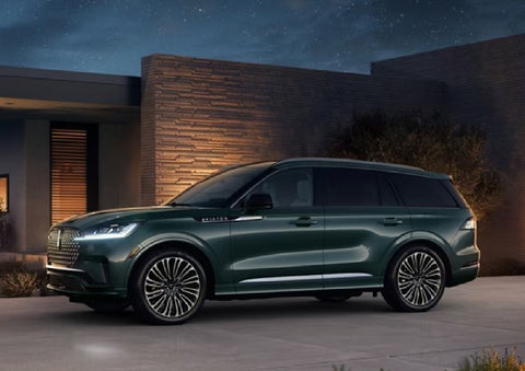 A green 2027 Lincoln Aviator® SUV is parked outside a contemporary home. | Koons Lincoln of Bethesda in Silver Spring MD