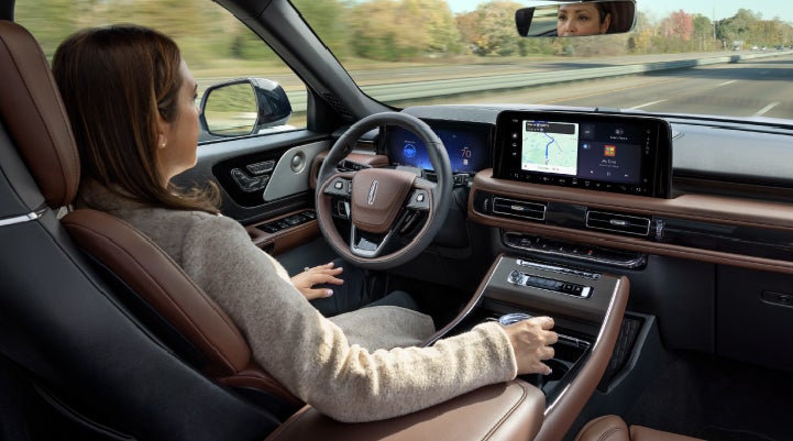 A 2027 Lincoln Aviator® SUV is being driven hands-free on a highway lined with trees. | Koons Lincoln of Bethesda in Silver Spring MD