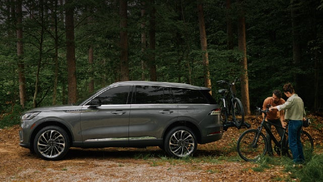 A father and son load e-bikes on a bike rack attached to a 2027 Lincoln Aviator® SUV. | Koons Lincoln of Bethesda in Silver Spring MD