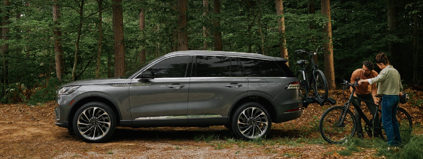 A father and son load e-bikes on a bike rack attached to a 2027 Lincoln Aviator® SUV. | Koons Lincoln of Bethesda in Silver Spring MD